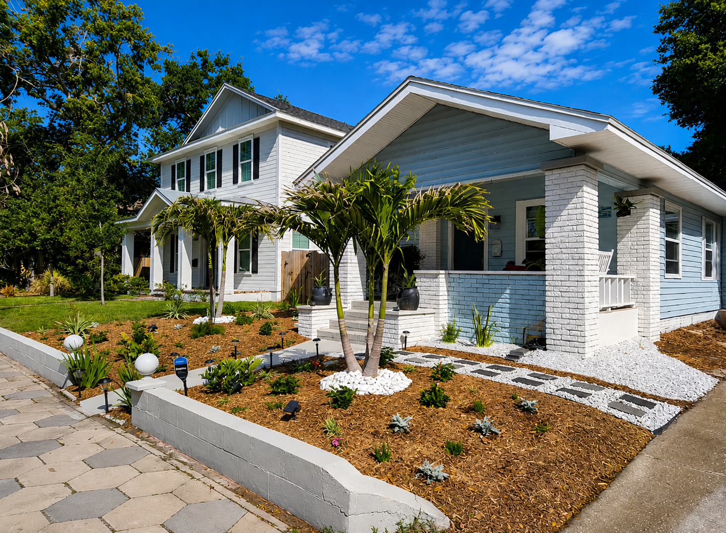 After: a lush, layered mulched garden bed lines the paver walkway to the porch