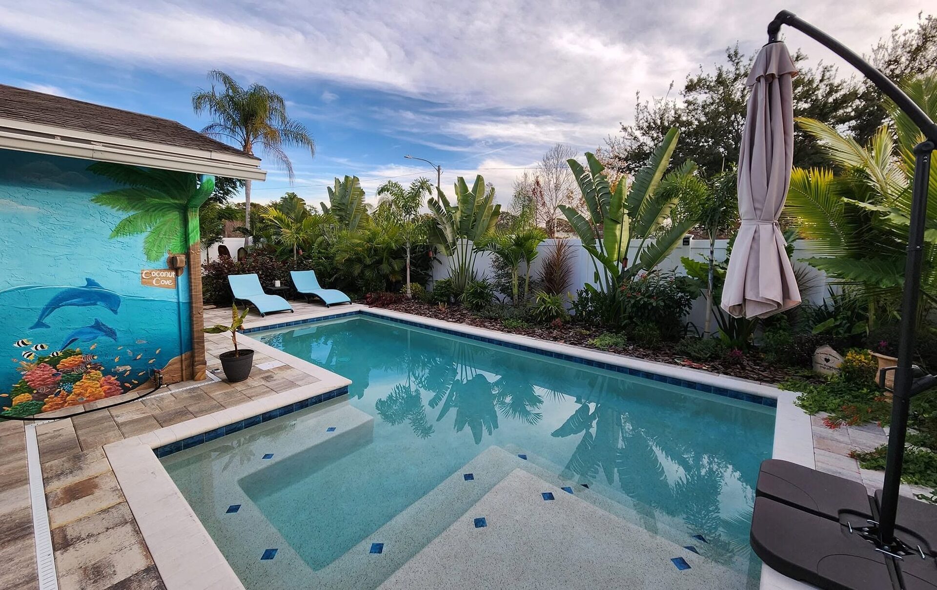 Welcoming Coconut Cove poolside garden with layered tropical planting and loungers